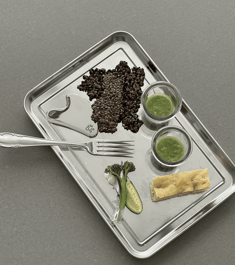 Edelstahltablett mit Gemüse, Snacks und Körnern sowie einer Gabel und einem Gua Sha