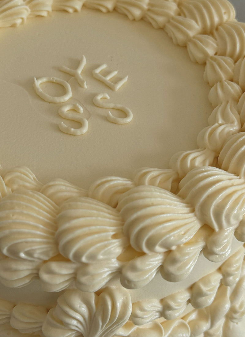 closeup einer cremefarbenen Torte mit der Aufschrift Oyess